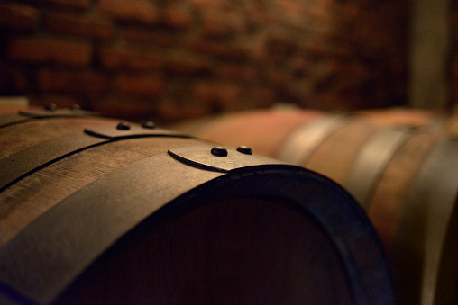Wooden wine barrels in a brick cellar. Low-key image.