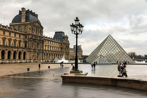 Paris, France - February 19, 2014: Beautiful view of tourists visiting the Louvre museum in Paris, France, on a cloudy day in February, 2014