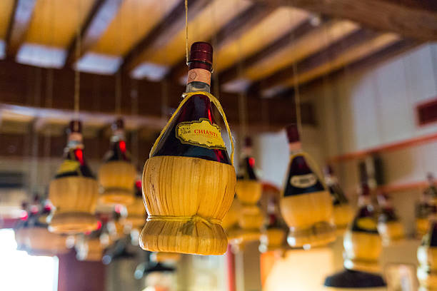 Wine Flask - Chianti View of Chianti bottles hanging from the ceiling wine italian culture wine bottle bottle stock pictures, royalty-free photos & images