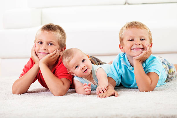 zwei jungen und ein baby liegen auf dem teppich - carpet floor lying down people stock-fotos und bilder