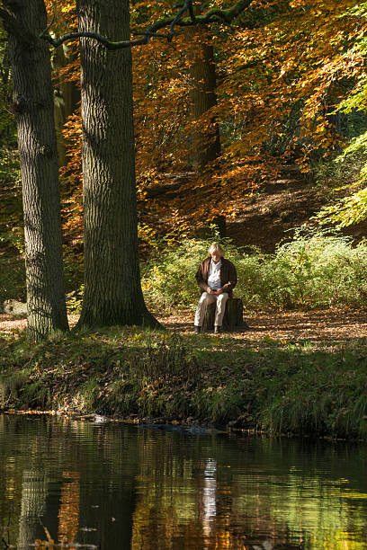 istock Mature men sitting on stump in the forest 499660100