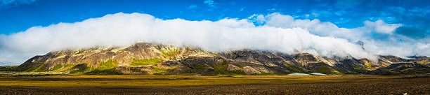 Photo of Clouds rolling over mountain ridge panorama to valley below Iceland