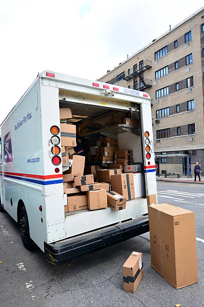 USPS Delivery man unloading boxes from truck New York, USA - December 3, 2015: USPS delivery man in truck full of boxes after black friday and cyber monday sales. Sitting on the ground beside the young man is a stack of sealed boxes. united states postal service photos stock pictures, royalty-free photos & images