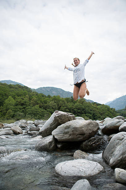 幸せな女性、川でジャンプスイス - arms outstretched teenage girls jumping flying ストックフォトと画像