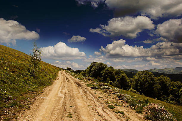 Summer mountin landscape with green grass, road and clouds stock photo