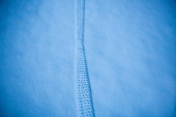 Low angle view of snowy, unused railroad tracks leading toward the Rocky Mountain foothills at sunset.