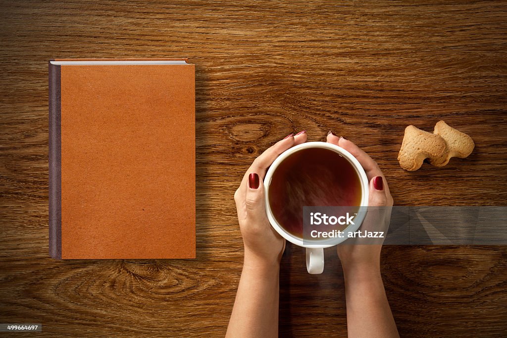 woman with cup of tea, cookies and book on wood woman with cup of tea, cookies and book on wooden table Adult Stock Photo