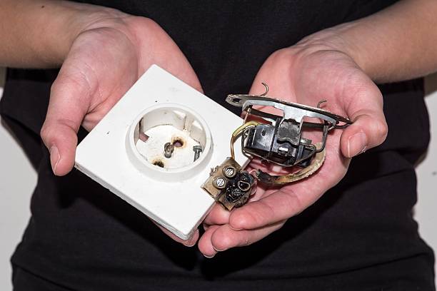 istock Person holding a damaged electric socket 499665013