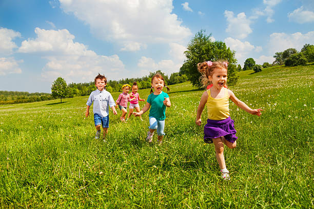 running kinder im grünen feld im sommer - friendship park flower outdoors stock-fotos und bilder