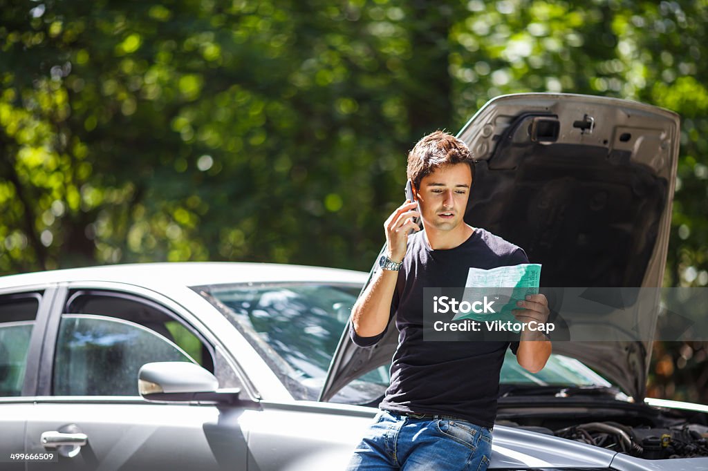 Handsome young man calling for roadside assistance Handsome young man calling for assistance with his car broken down by the roadside Breaking Stock Photo