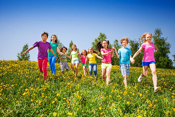 istock Running happy kids holding hands in green field 499666647