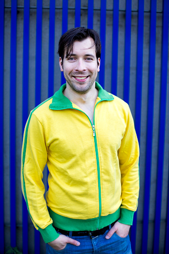 portrait of man in yellow trikot in front of blue wall