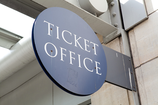 This image shows a ticket office sign on the outside of a building in the city.