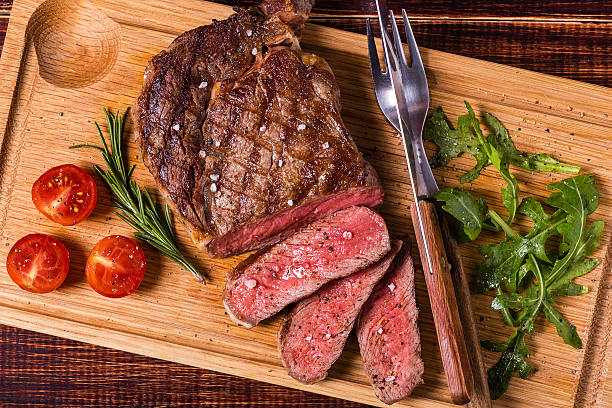 rib-eye-steak mit rucola-salat und tomaten. - butchers block stock-fotos und bilder