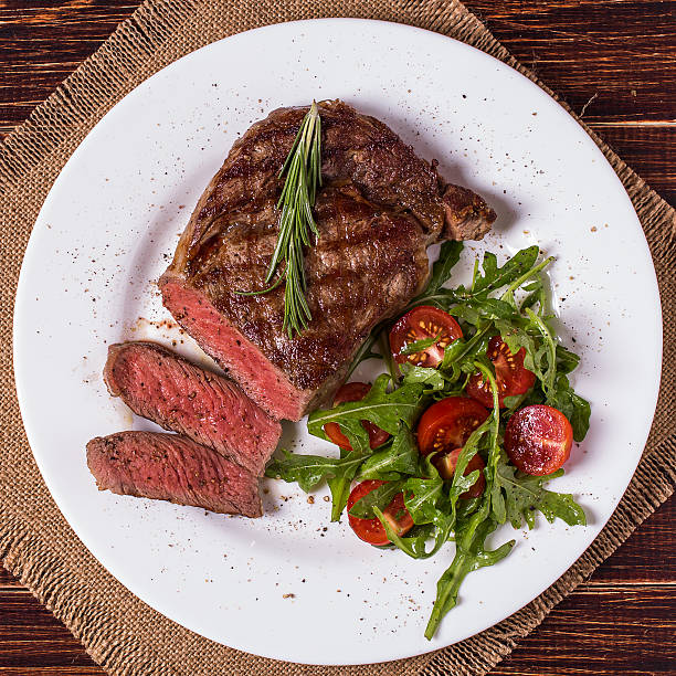 istock Ribeye steak with arugula and tomatoes. 499686824