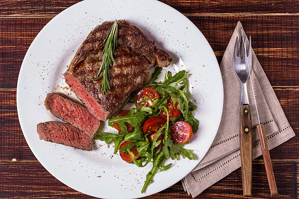 istock Ribeye steak with arugula and tomatoes. 499686868