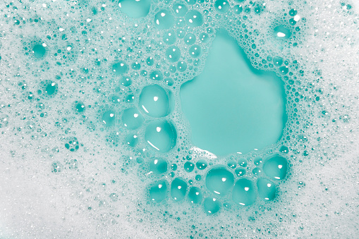 Close-up of soap bubbles with water on a blue background.