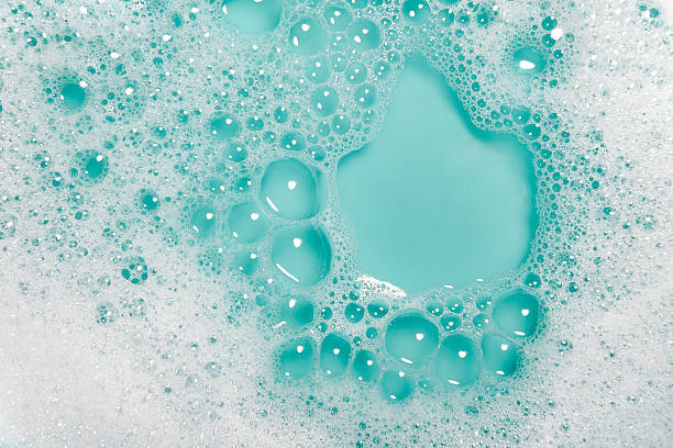 Soap bubbles background (blue) Close-up of soap bubbles with water on a blue background. laundry detergent stock pictures, royalty-free photos & images