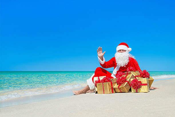 istock Christmas Santa Claus with gift boxes resting at ocean beach 499693956