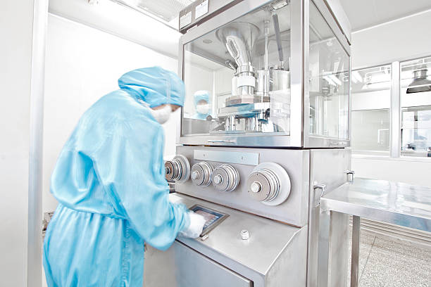 pharmaceutical factory equipment working in clean room pharmaceutical factory equipment working with unrecognizable technician in blue cleanroom stock pictures, royalty-free photos & images