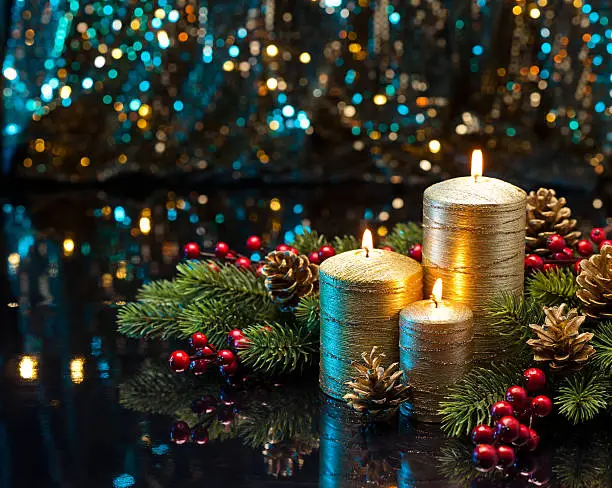 Three golden Candles with Christmas tree branches and pine cones decorated