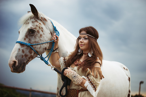 Indian girl with white  horse on sky background