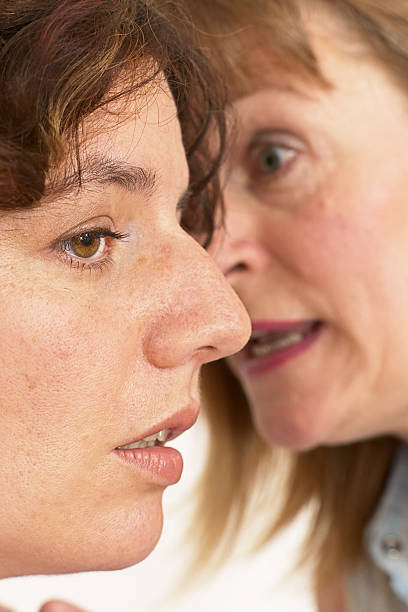 two women whisper a secret stock photo