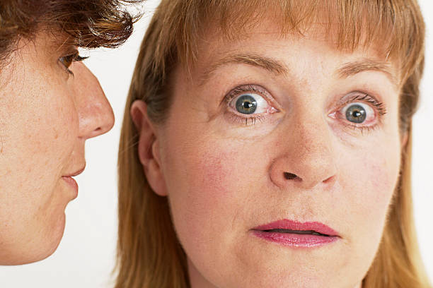 two women whisper a secret stock photo