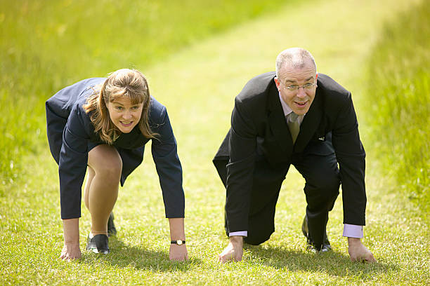 Business man and woman line up to compete in race stock photo