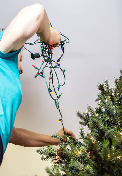istock Woman Decorating Christmas Tree With Electric Christmas Lights 499718952