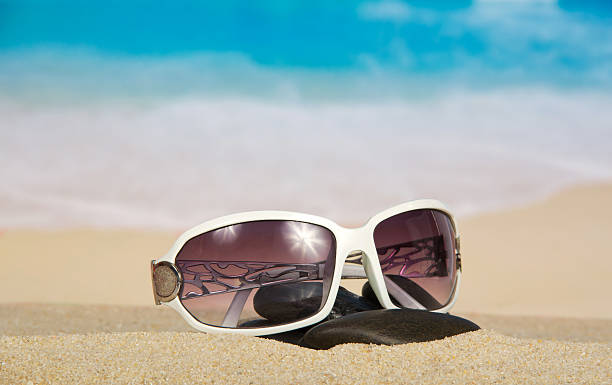 istock Sunglasses and pebbles on sand 499719557