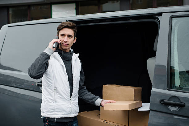 profissional courier perto da van com caixas chamar por telefone - moving van moving office moving house truck imagens e fotografias de stock