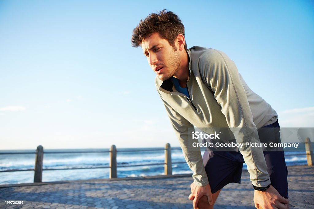 Just keep going Low angle shot of a handsome young man taking strain from his morning run Active Lifestyle Stock Photo