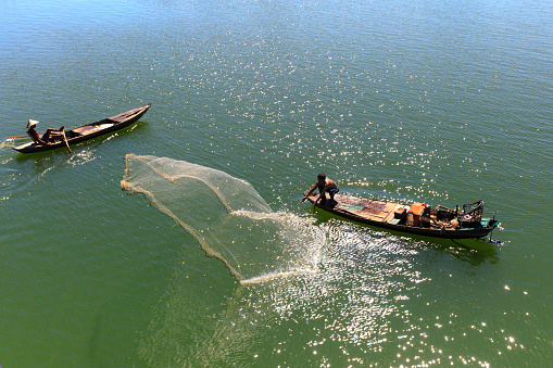 Tri An lake, Dong Nai Province, Vietnam - November 19, 2015: Two men cast their nets fishing on the Tri An reservoir. This is the daily work of people from fishing village