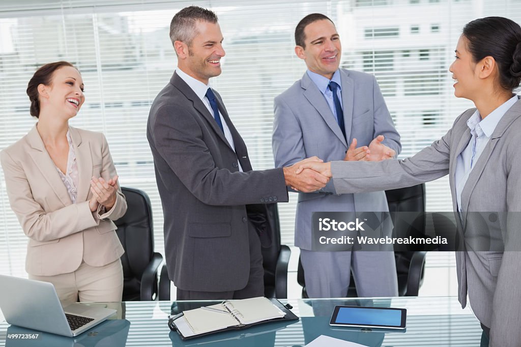 Smiling future workmates shaking hands Smiling future workmates shaking hands in bright office 20-29 Years Stock Photo