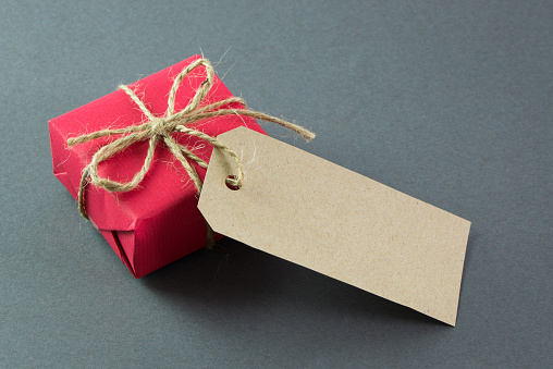 Red gift box with tag on grey background