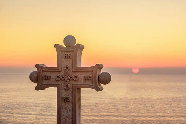 istock Stone cross with symbols on it on sundown 499730324