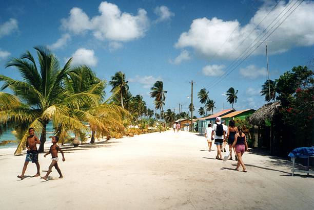 Saona, Dominican Republic - May 3, 2002: Locals and tourists walking on a sandy road at a small village on Saona Island, a tropical island located on the south-east tip of the Dominican Republic. It is a government protected nature reserve and is part of Parque Nacional del Este.