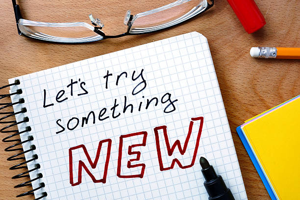Notepad with  let’s try something new  on office wooden table.