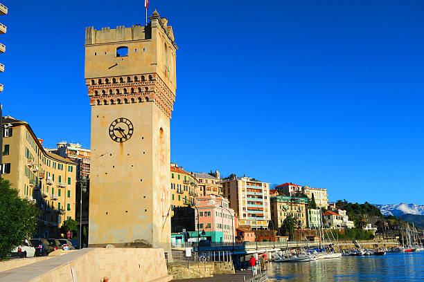 View of the tower and  port of Savona, Liguria, Italy Savona,Italy,22 november 2015. View of the port of Savona, Liguria, Italy with foreground characteristic tower Leon Pancaldo (XIV century).This tower, formerly called Quarda Tower, is mentioned for the first time in a document of 1392 and was part of the walls to protect the city, in a strategic position for the defense of the city and harbor. After the destruction of the walls by the Genoese in 1527 the tower was isolated and in the following centuries suffered a series of alterations. The tower is now dedicated to Leon Pancaldo, Savona navigator who accompanied Ferdinand Magellan on his first circumnavigation around the world. The building has a square plan of about six meters wide, is about twenty three meters high and is considered the symbol of the city. province of savona stock pictures, royalty-free photos & images