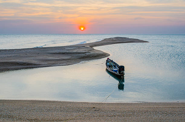 A long-tailed boat is cast anchor on the sunset beach at Koh-nokpao, Surat thani, Thailand.