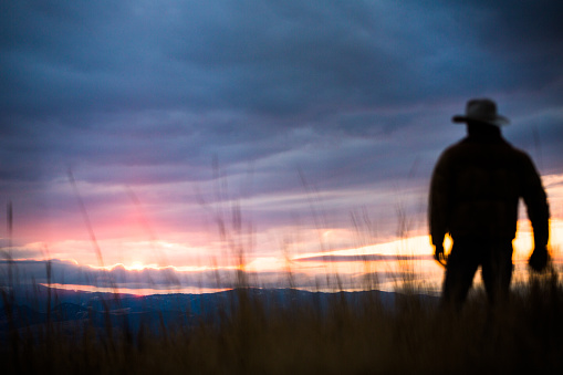 Silhouette of man watching sunset over distant mountains