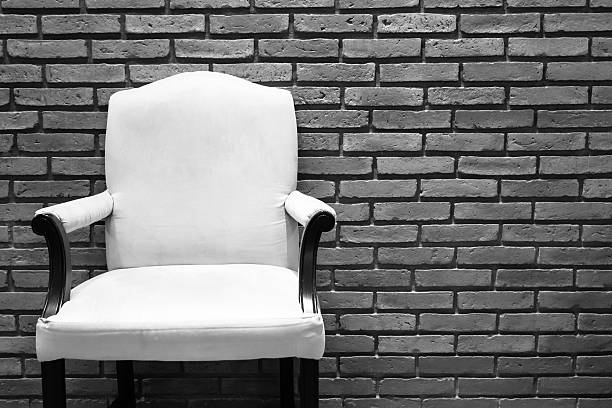White chair in front of grey and white brick wall.