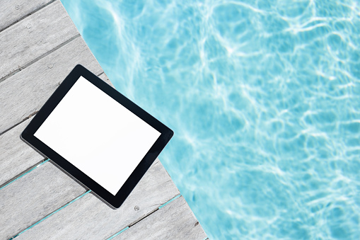 Tablet computer with empty screen on the wooden pool deck