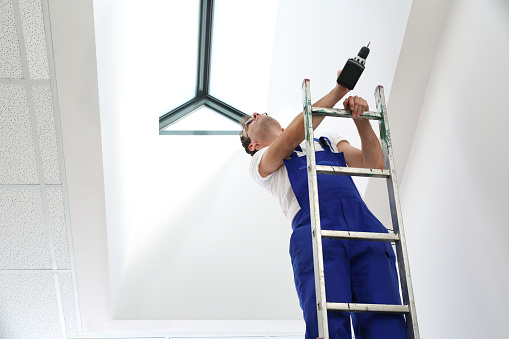 Hombre vestido de trabajo de trabajo en la instalación de techo ventanas photo