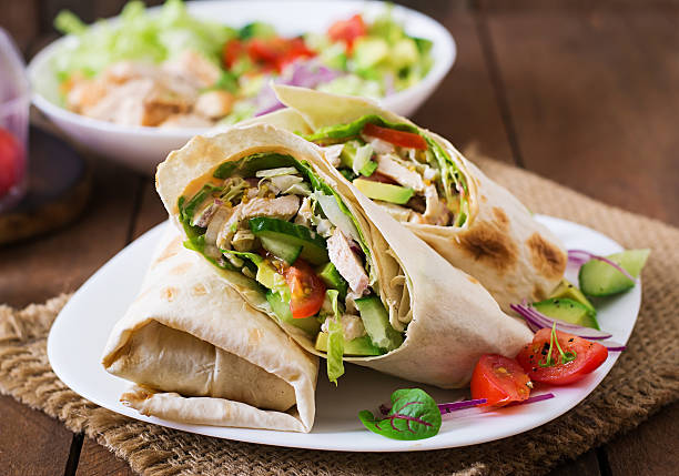 tortilla avvolge fresche con pollo e verdure fresche sul piatto - sandwich healthy eating wrap sandwich food foto e immagini stock