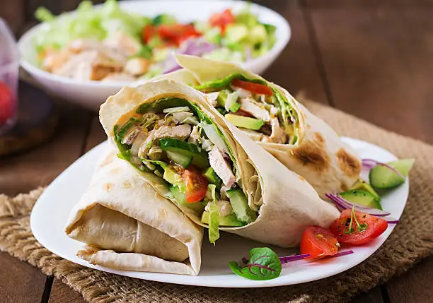 Photo of Fresh tortilla wraps with chicken and fresh vegetables on plate