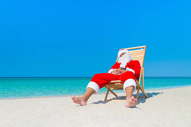 istock Christmas Santa Claus resting on deckchair at ocean sandy beach 499743214