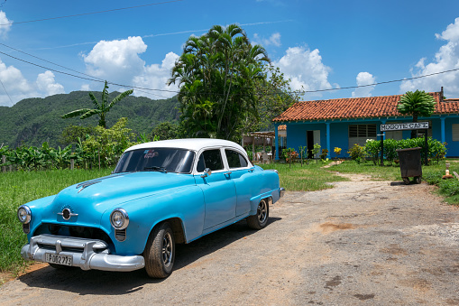 Vinales, Сuba - June 26, 2015: A classic american car parked in front of a local cafè with the Mogotes on the background in Vinales valley, Cuba.