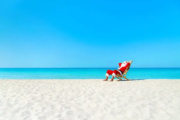 Photo of Christmas Santa Claus resting on deckchair at ocean sandy beach